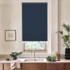 Dark navy roller blind covers top of a window above a kitchen sink, partially blocking outside view; marble countertop, stainless faucet, wooden cabinets, potted plants and framed sketch nearby.
