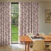Floor-length pleated curtains, pink with brown bamboo print, partly drawn across a window; they filter daylight into a dining room with wooden table, beige chairs, parquet floor, grassy backyard.