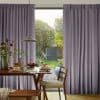 Floor-length pleated lavender-gray curtains on a track, drawn open at center to frame glass doors; admitting daylight into a dining area with table, pancakes, pendant lamp and sunlit garden.