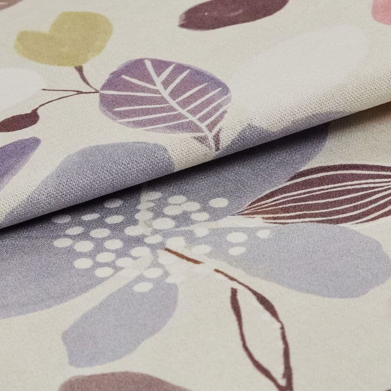Folded woven fabric sample with pastel leaf-and-dot print — layered and overlapping, revealing textured weave — close-up macro on a neutral surface, softly lit to emphasize pattern and folds.