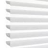 Horizontal zebra (dual-layer) roller blind at the left edge with alternating sheer and opaque stripes, aligned to filter and diffuse bright daylight; close-up, minimal interior against a white background.