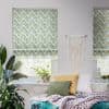 Chevron-patterned Roman shades cover the upper window panels, partially lowered and filtering daylight; a boho bedroom nook with macramé wall hanging, potted plants, cushions, and a chunky knit throw.