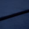 Navy-blue soft fabric, folded into overlapping layers creating a diagonal ridge and subtle shadow, showing a fine, slightly nappered texture; close-up studio view with soft, even lighting.