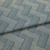 Blue-and-cream woven fabric with interlocking rectangular striped pattern, partially folded and layered, showing raised texture and seam — close-up on a flat surface under soft studio lighting.