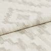 Woven upholstery fabric with light beige geometric motif, folded over once showing textured weave; close-up studio shot with neutral lighting emphasizing fibers and subtle pattern.